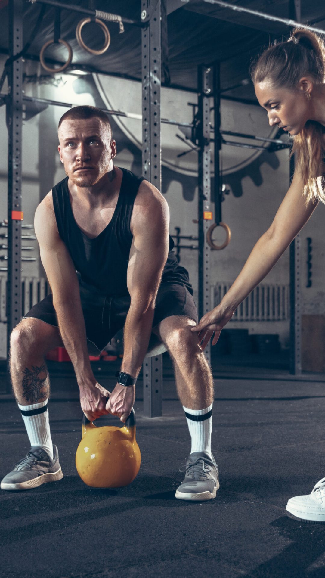 Athletic man and woman with a dumbbells training and practicing in gym. Concept of sport, healthy lifestyle, wellbeing.